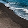 Soft waves lapping against a black sand beach on the lava island of Nea Kameni situated in the heart of the Santorini Caldera